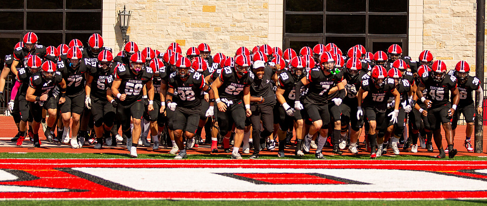 Carthage football players racing onto the football field.