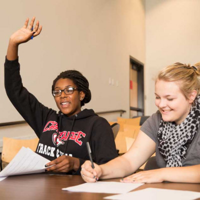 Student raising their hand in a classroom.
