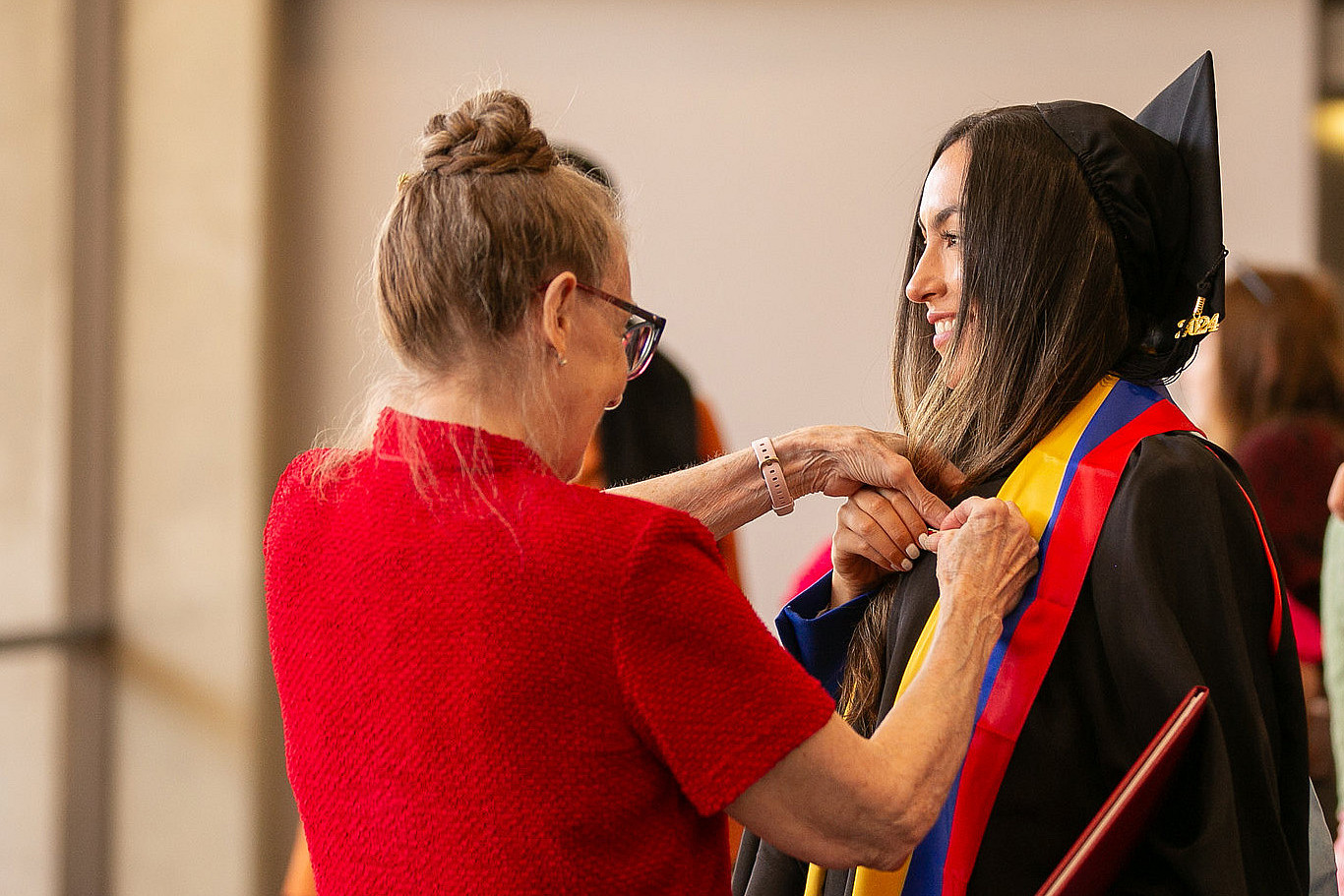 A Carthage graduate places a pin on a graduating students gown