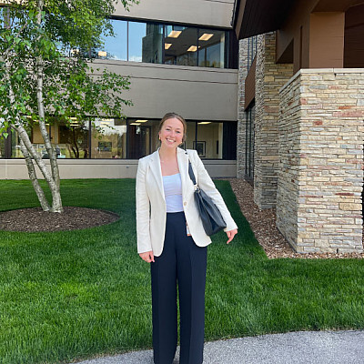 A female student in professional clothes outside an office building.