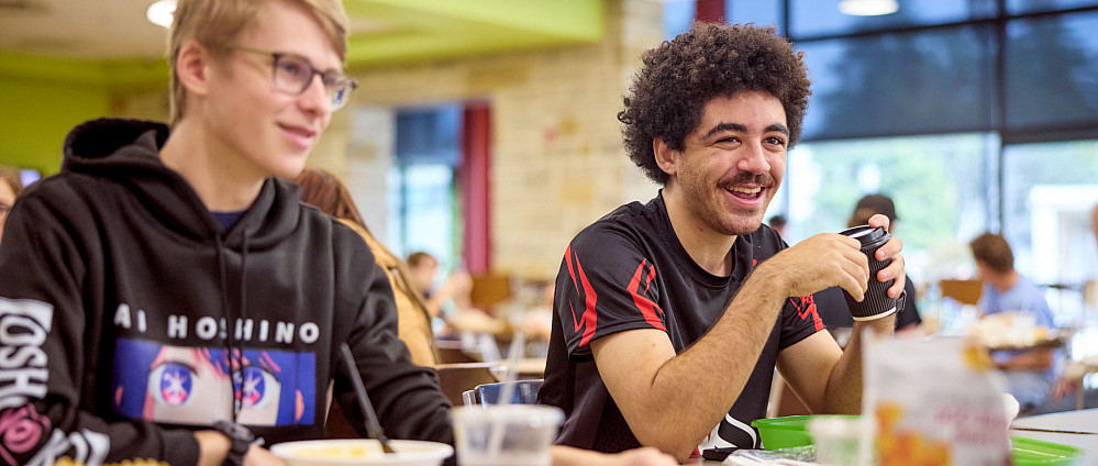 Two students enjoying a meal in the campus cafeteria.