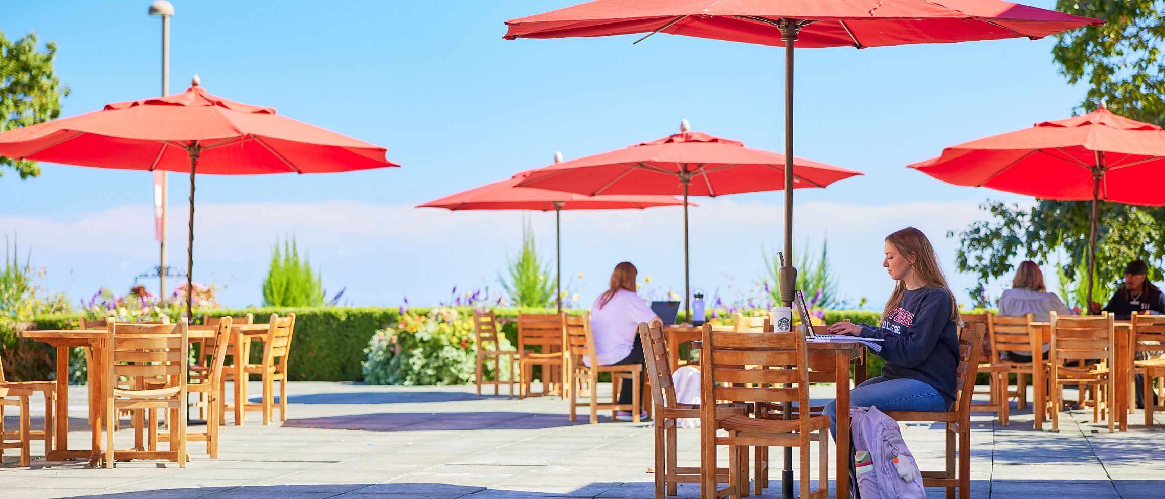 A student sitting at a table on a patio overlooking Lake Michigan.
