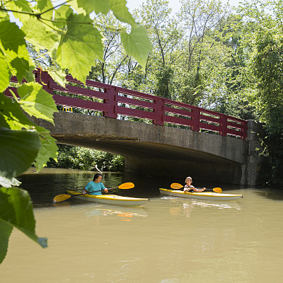 Students kayak along the Pike River under Carthage's red bridge.