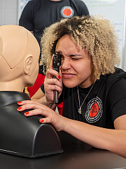 A student in allied health science examines a mannequin.