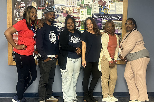 Six educators pose in front of a bulletin board.
