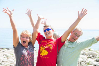 A student and his parents waving their hands next to Lake Michigan.